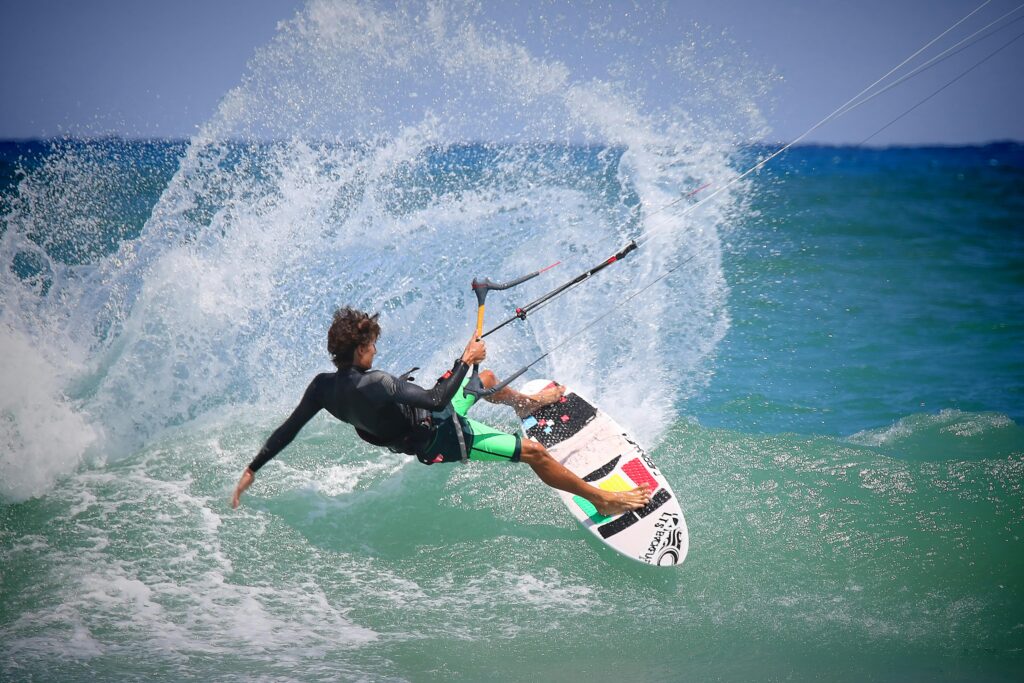 A kiteboarder performing thrilling maneuvers on ocean waves on a sunny day.